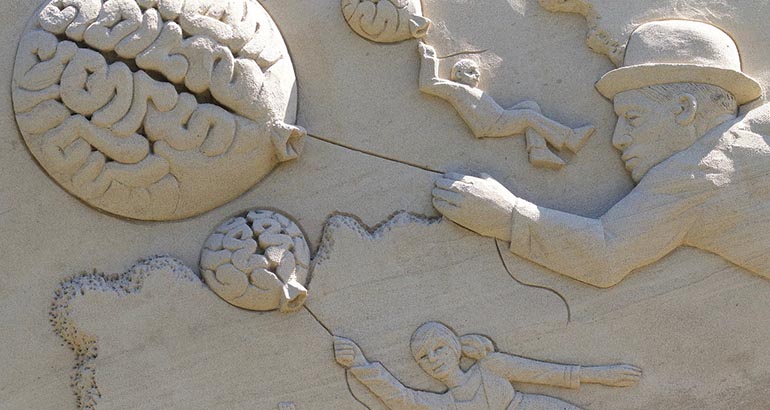 Escultura de personas sosteniendo globos en forma de cerebros