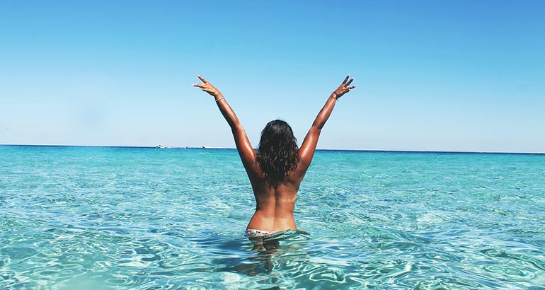 mujer con los brazos levantados en el mar